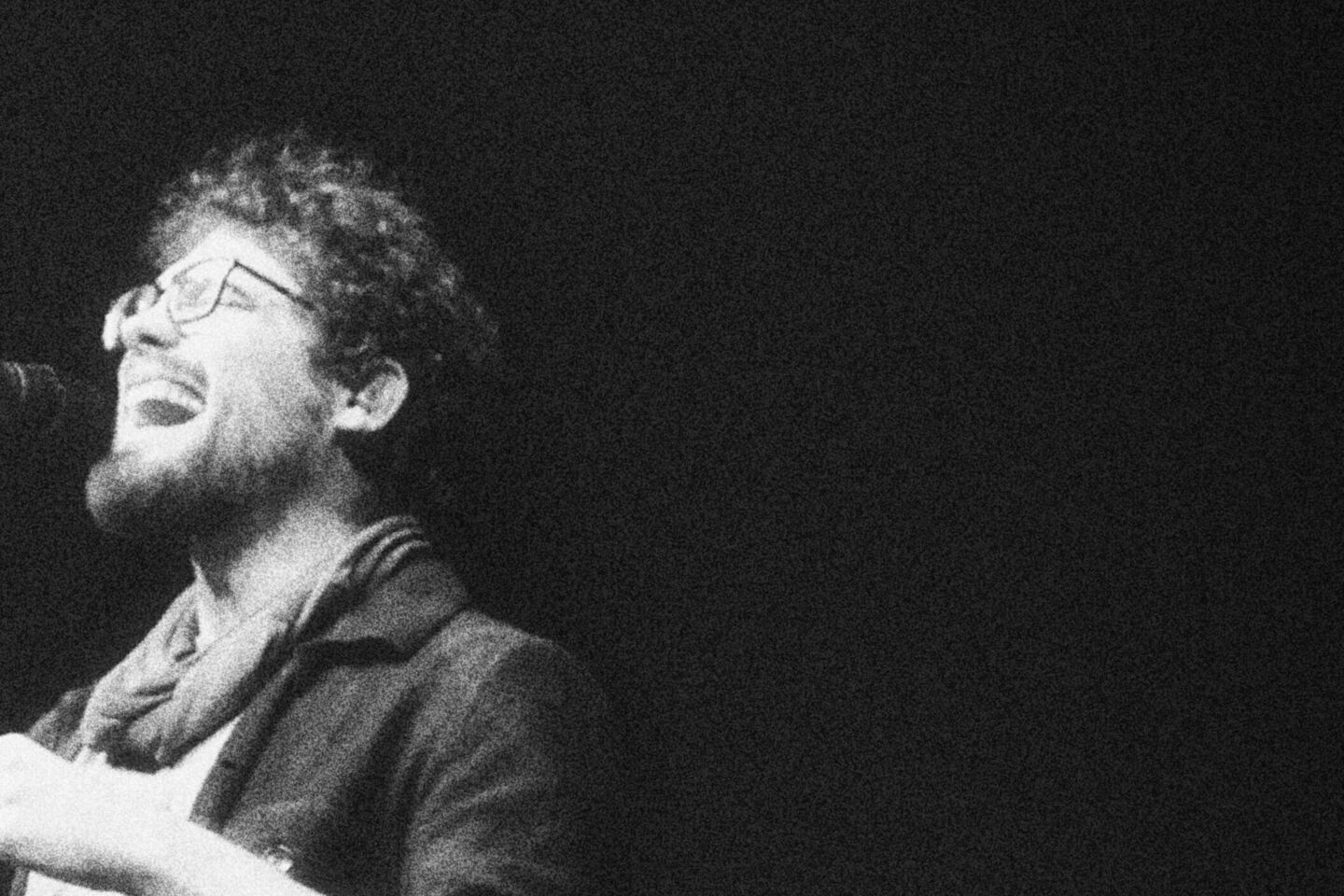 Schwarzweißfoto von Adrian Goldner, der mit offenem Mund in ein Mikrofon singt