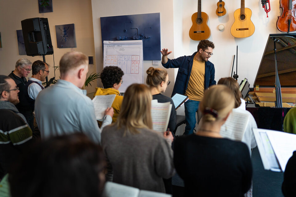 Adrian Goldner leitet eine stehende Gruppe beim Singen im Workshop